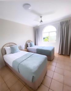 a hotel room with two beds and a window at Toscana Village Resort in Airlie Beach