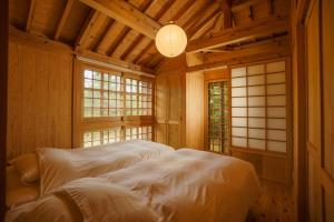 a bedroom with a bed in a room with windows at かたあきの里 in Miyako-jima