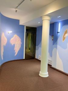 a room with a column and a wall with wings at The Top Hostel in Tashkent