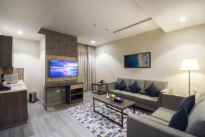 a living room with a couch and a tv at Enala Hotel - Al Khobar in Al Khobar