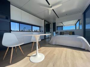 sypialnia z łóżkiem oraz białym stołem i krzesłami w obiekcie oasis noosa - luxury floating eco villas w mieście Noosa Heads