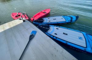 duas canoas ao lado de um barco na água em oasis noosa - luxury floating eco villas em Noosa Heads