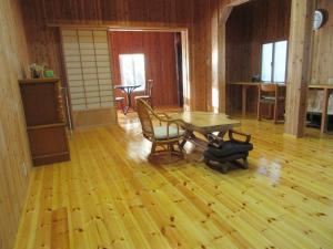 Habitación con suelo de madera, mesa y sillas. en 民泊くま - 絵画と音楽の宿 en Inawashiro