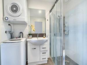 a white bathroom with a sink and a shower at 806/67 Arvia in Newcastle