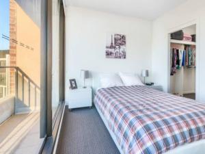 a bedroom with a bed and a balcony at 806/67 Arvia in Newcastle