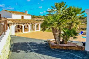 una palmera frente a una casa en Rosalia - holiday home with panoramic view and private pool in Teluda, en Teulada