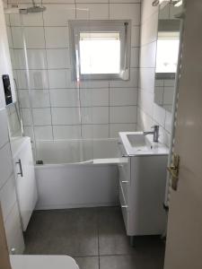 a white bathroom with a tub and a sink at LES BALCONS ROUGES - FACE MER in Sainte-Cécile-Plage