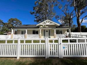a white picket fence in front of a white house at Hunter Valley D'Vine Stay II in Nulkaba