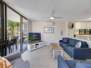 ein Wohnzimmer mit einem blauen Sofa und einem TV in der Unterkunft Blue Horizon Unit 1 Bulcock Beach QLD in Caloundra