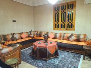a living room with brown leather couches and a table at villa OUSSAMA in Marrakesh