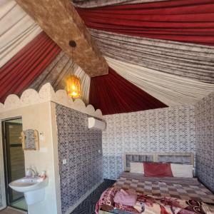 1 dormitorio con 1 cama y techo con cortinas rojas en Dream Bedouin life camp en Wadi Rum