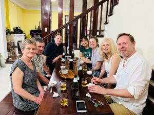 a group of people sitting around a table with drinks at Maison Vu Tri Vien in Hue