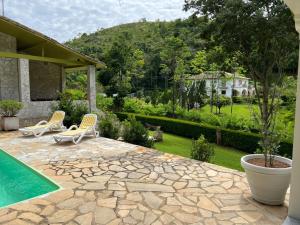 a patio with two chairs and a swimming pool at Canto das Estrelas in Secretário