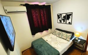 een slaapkamer met een bed en een flatscreen-tv bij Apto Executivo Ravena in Campo Grande