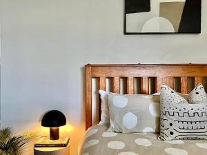 a bedroom with a bed with white pillows and a lamp at Elegant Federation Home Near The Airport in Sydney