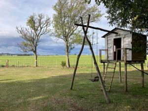 a tree house with a swing in a field at Casa de campo rústica in Tandil