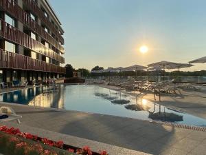 a swimming pool with tables and umbrellas and a building at Paradiso Aparthotel - Private apartment-BSR-1 in Nesebar