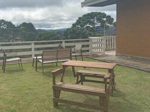 uma mesa de piquenique em madeira e bancos num pátio em Pousada Campos SONHO MEU em Campos de Jordão
