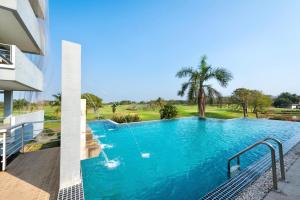 a large blue swimming pool next to a building at Uniland Golf & Resort in Nakhon Pathom