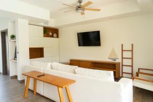a living room with a white couch and a tv at Villas La Mar in Monterrico
