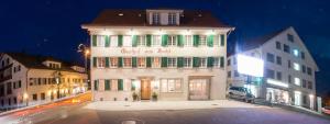 a large white building with green shutters on a street at Gasthof zum Hecht in Fehraltorf