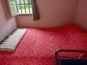 a red bed in a room with a window at Las Horquetas casa de campo in Yala