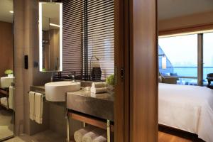 baño con lavabo, cama y espejo en Renaissance Hong Kong Harbour View Hotel, en Hong Kong