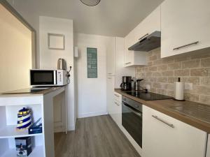 eine Küche mit weißen Schränken und einer Mikrowelle in der Unterkunft Appartement rénové 5 personnes avec balcon au centre de Perros-Guirec - FR-1-368-382 in Perros-Guirec