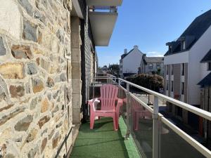 dwa różowe krzesła siedzące na balkonie budynku w obiekcie Appartement rénové 5 personnes avec balcon au centre de Perros-Guirec - FR-1-368-382 w mieście Perros-Guirec