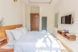 um quarto com uma cama branca e uma televisão em Bách Tùng Viên Villa Đà Lạt em Ấp Kim Thạch