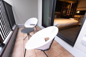 Duas cadeiras brancas e uma mesa numa varanda em N Plus Hotel Akihabara em Tóquio