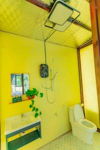 a yellow bathroom with a toilet and a sink at Phuong Nam Gia Trang Farmstay in Gia Nghĩa