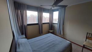 1 dormitorio con 1 cama y 2 ventanas en Balcarce I en Córdoba