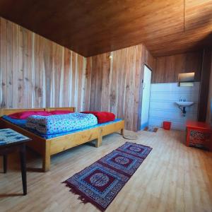 una camera con un letto in una stanza con pareti in legno di Lali Gurash Homestay - Okhrey a Sombāri