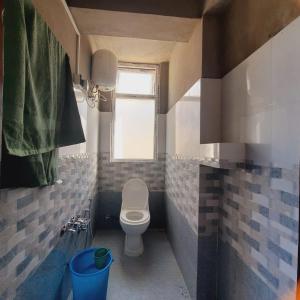 a small bathroom with a toilet and a window at Lali Gurash Homestay - Okhrey in Sombāri