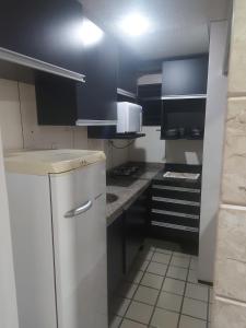 uma pequena cozinha com armários pretos e electrodomésticos brancos em Flat Number One - Ponta D'areia - Ferreira Hospedagens em São Luís