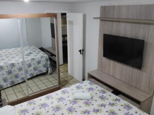 a bedroom with a bed and a tv and a mirror at Flat Number One - Ponta D'areia - Ferreira Hospedagens in São Luís