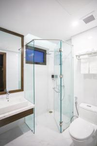 y baño con ducha de cristal y aseo. en Minh Quan Hotel - Da Nang Center By HOS en Da Nang