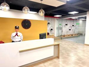 ein Mann steht hinter einer Theke mit einer Uhr an der Wand in der Unterkunft Espectacular vista cerca a cable plaza con Piscina in Manizales