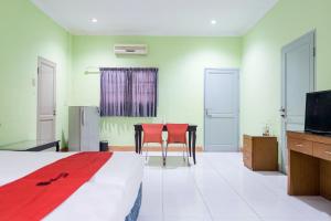 a bedroom with a bed and two chairs and a television at RedDoorz Plus @ Jalan Iskandar Muda Medan in Medan