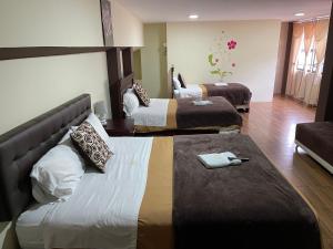 ein Hotelzimmer mit 2 Betten und einem Sofa in der Unterkunft Hotel Casa Santa Lucía in Baños