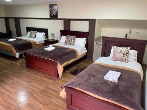 a hotel room with two beds and wooden floors at Hotel Casa Santa Lucía in Baños