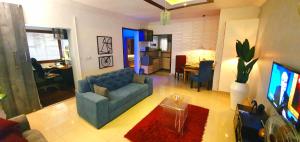uma sala de estar com um sofá azul e uma televisão em House of Dioma Apartments, Kubwa em Abuja