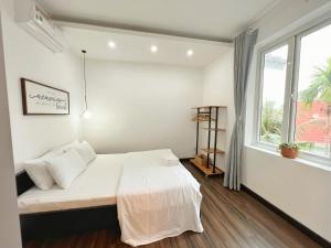 a white bedroom with a bed and a window at Contemporary Greenhouse Garden Villa- 4 bedrooms Villa in Vung Tau