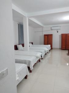 fila de camas en una habitación con paredes blancas en Thành Luân Hotel, en Bak Kan