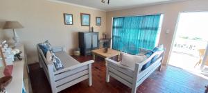 een woonkamer met 2 witte stoelen en een tafel bij Pik 'n Wyntjie in Gansbaai