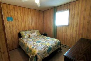 ein Schlafzimmer mit einem Bett in einer Holzwand in der Unterkunft Peaceful & Private Cabin close to the Lake in Matlock