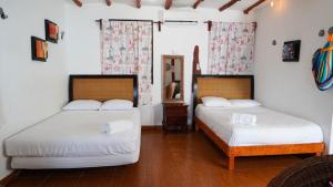 two beds in a room with white walls and wood floors at Choby's House Holbox in Holbox Island +68 photos