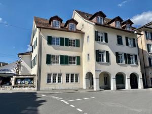 a large white building with green windows on a street at Business Apartment ZIMMERzuVERMIETEN in Solothurn in Solothurn