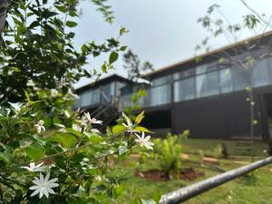 a black building with white flowers in front of it at Phuong Nam Gia Trang Farmstay in Gia Nghĩa